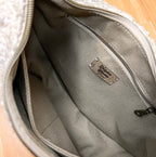 Close-up of the interior of a gray textured bag with a zippered pocket and a metal brand plaque reading 'Siberian Wolf'.
