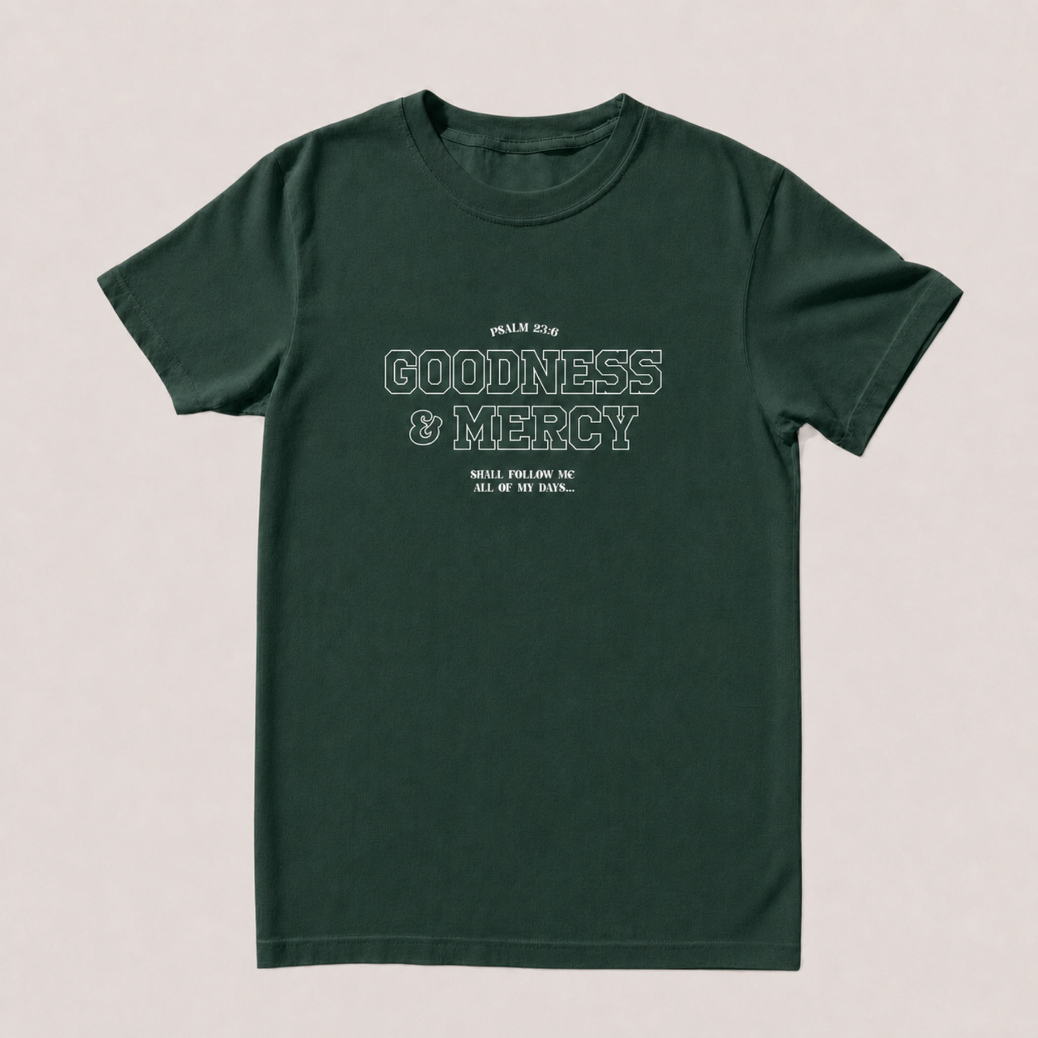 A dark forest green short-sleeve t-shirt with a distressed white graphic print on the front reading 'GOODNESS & MERCY' and 'Shall  FOLLOW me ALL of MY DAYS.