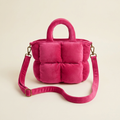 Pink quilted handbag with a strap on a beige background