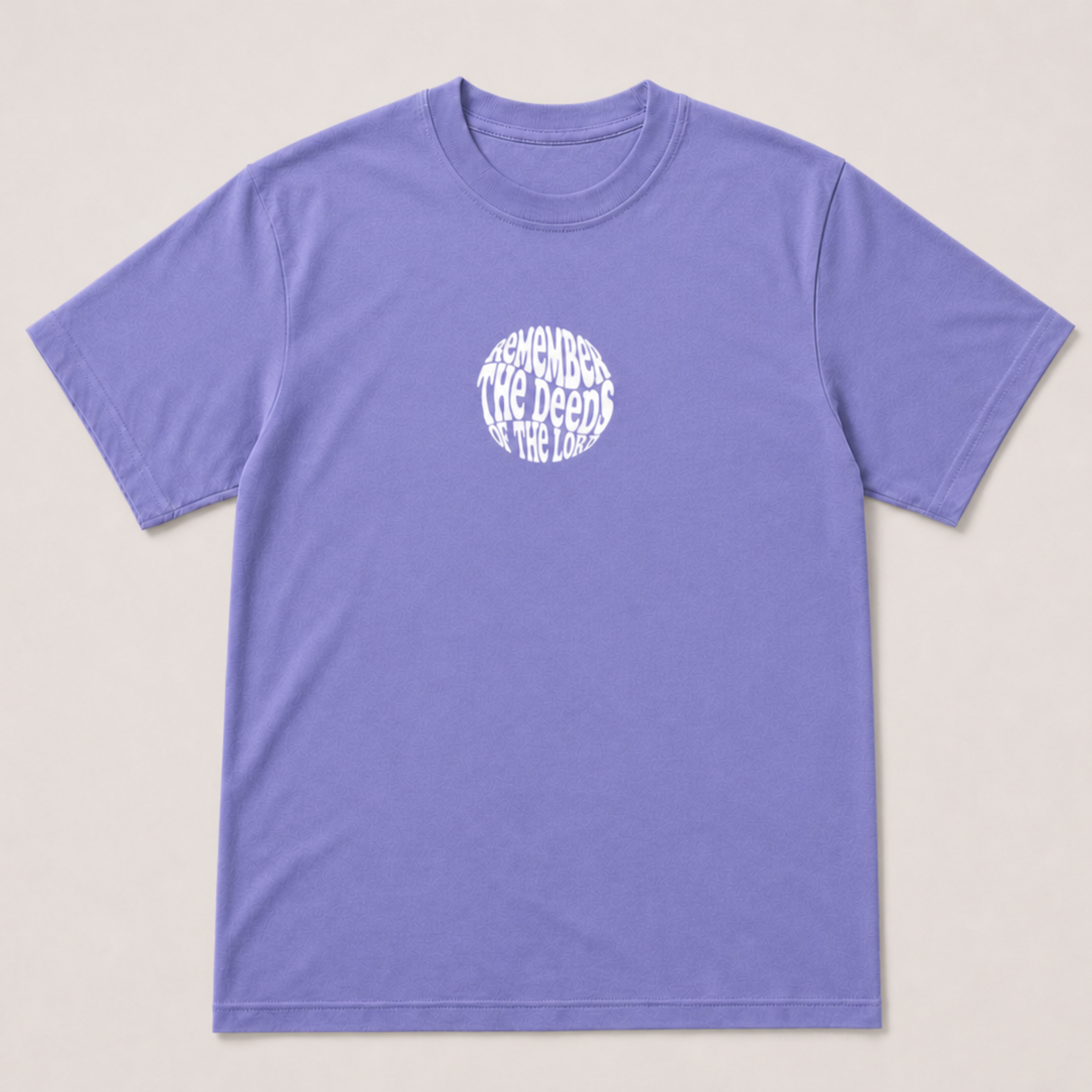 A light purple short-sleeve crewneck t-shirt with a white circular graphic on the chest containing the text 'remember the deeds of the Lord,' displayed flat against a light beige background.